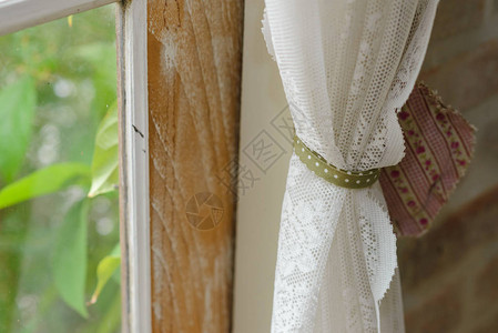 窗口上透明白色带条的紧闭处以旧样式装饰窗帘和背景图片