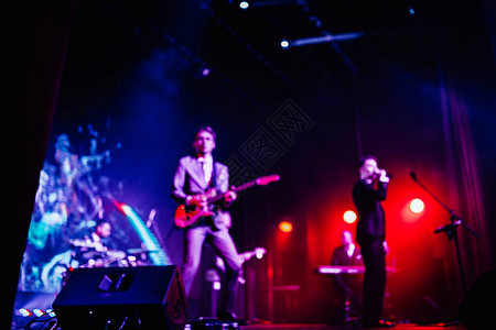 歌手和摇滚乐队在明亮聚光灯的红蓝紫色灯光下在舞台上表演的模糊明图片