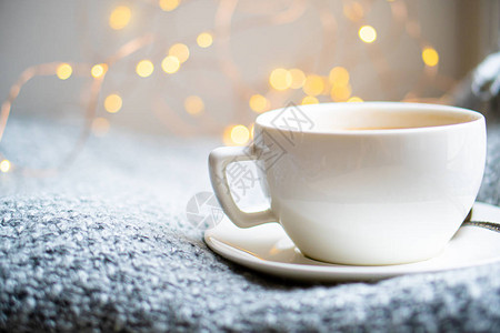 一杯加牛奶的咖啡在舒适的编织的冬毯子上图片