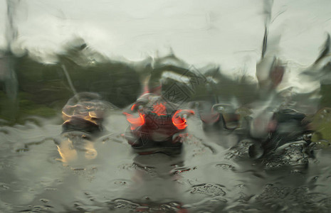 通过挡风玻璃在大雨中有汽车和行图片