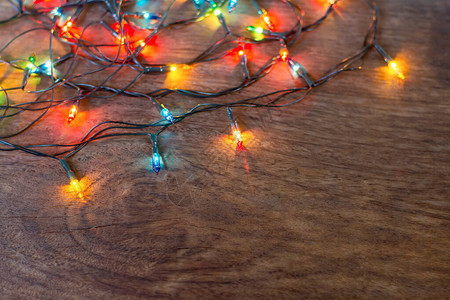 黑色木背景上的多彩的圣诞灯平面背景图片