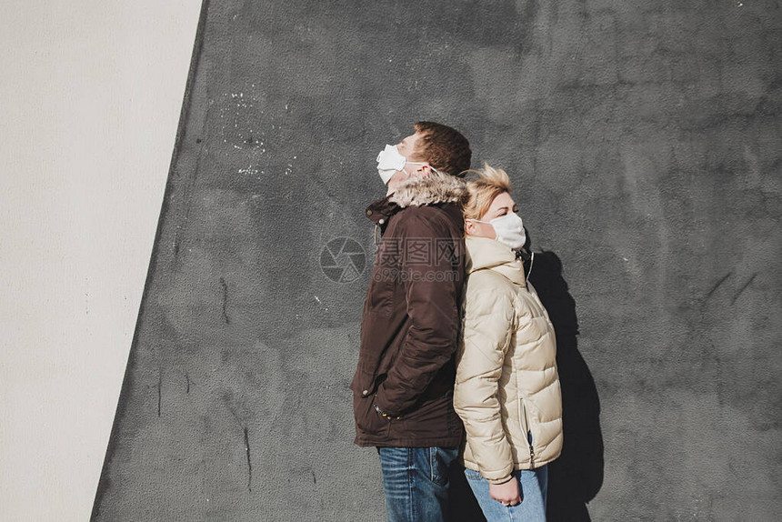 保护医疗面具中的夫妇背靠站在一起在街上环境污染的概念图片