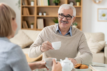 快乐的退休男子用茶杯看着他的女儿图片