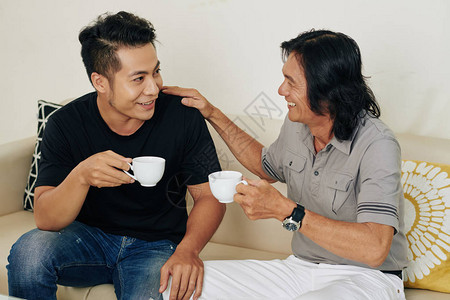 快乐的父亲和儿子享受咖啡讨论新闻计图片