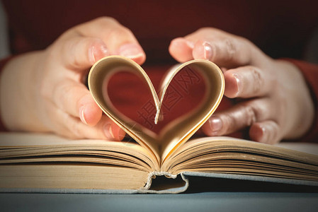 爱读书的概念女人拿着书页以心形的式图片