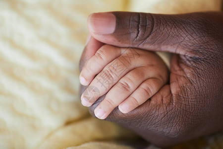 非洲男手牵新生儿小手的特写图片