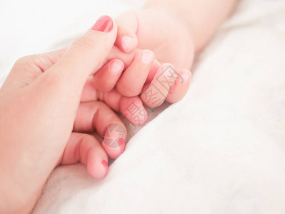 妈握着刚出生的婴儿的手特写一个写作的地方放置文字散焦婴儿的手握图片