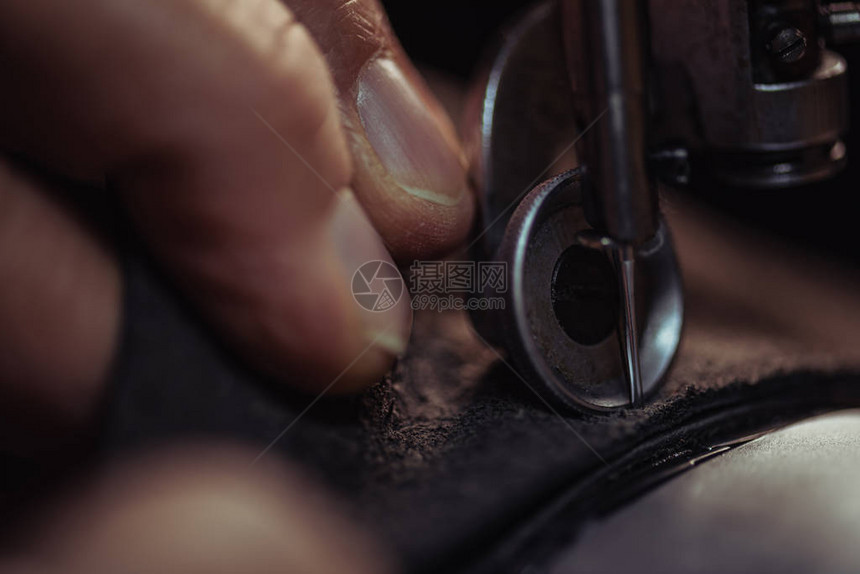 鞋匠在缝纫机上缝制真皮的近景图片