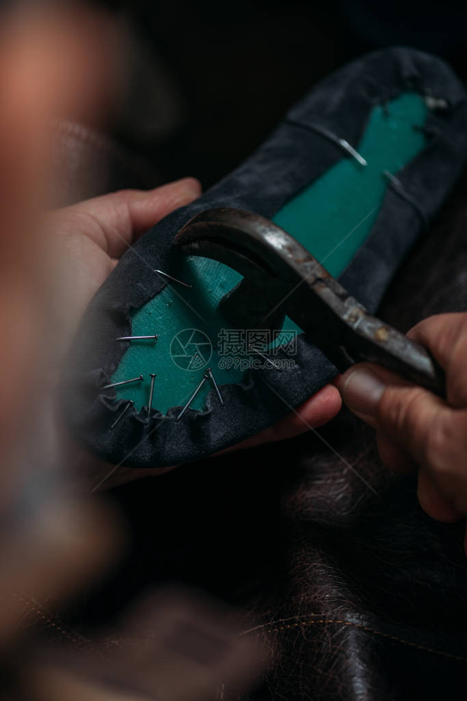 鞋匠用拔钉器从靴子上取下钉子的裁剪视图图片