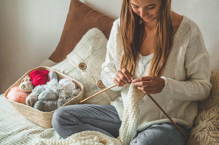 美丽的女孩在床上织暖和的毛衣以编图片