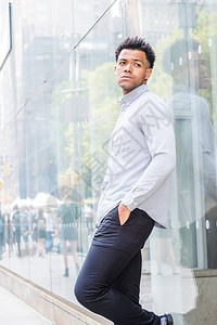 年轻的混血美国男子身穿浅灰色长袖衬衫黑色裤子背景图片