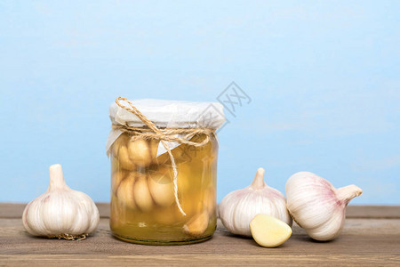 封闭玻璃罐中的大蒜和木制桌上新鲜的健康的发酵图片