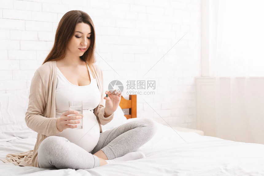 孕妇维生素期待女士服用一堆药丸和一杯水图片