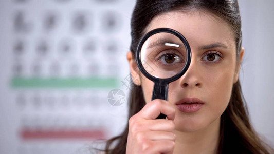 年轻妇女通过放大镜视力检查图片