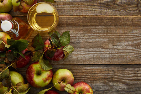 靠近木质表面的瓶子和玻璃新鲜苹果杯的成熟图片