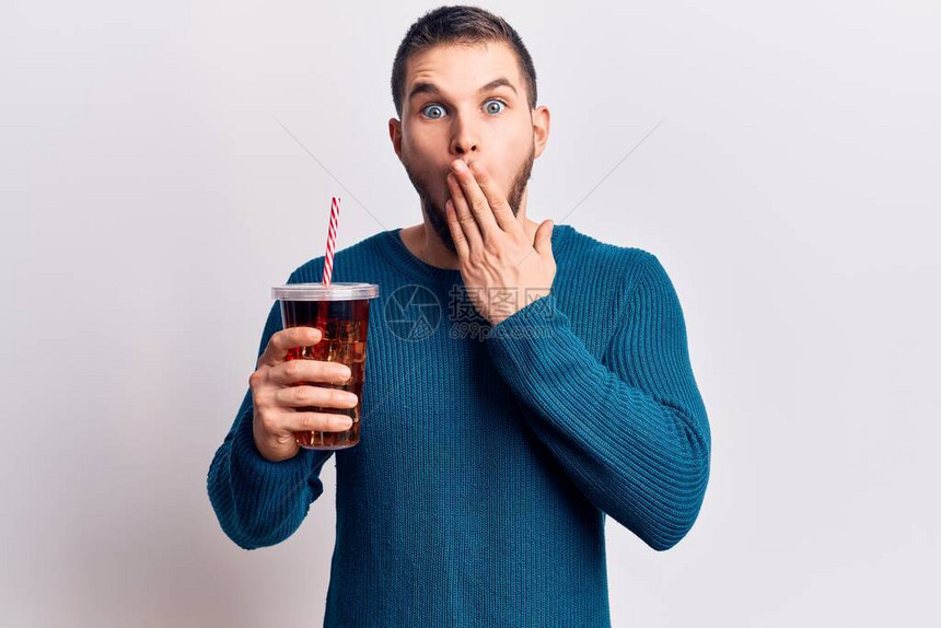 年轻英俊男子在喝可乐饮料时用手遮住嘴惊吓和害怕错误图片