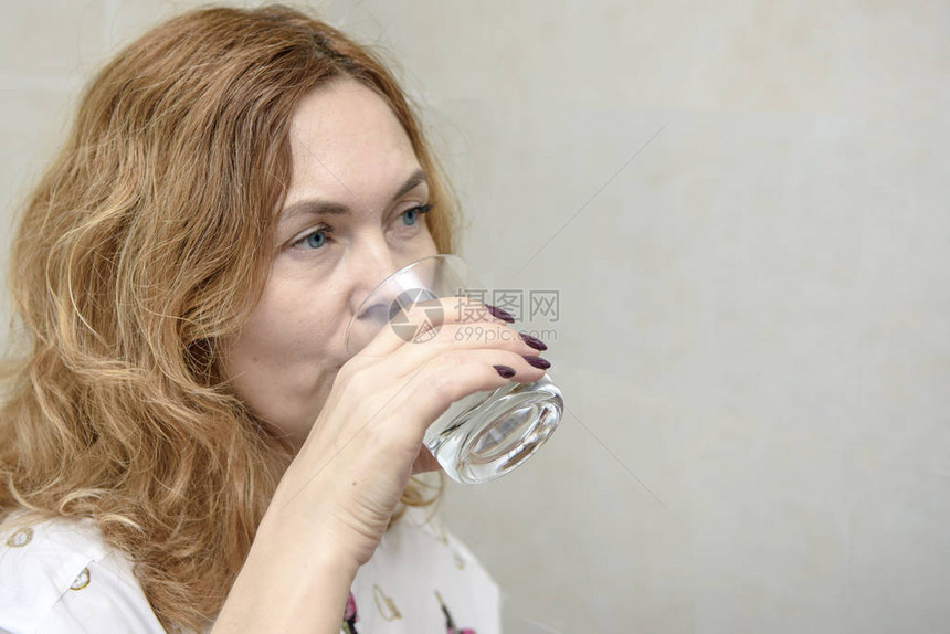 一位金发碧眼的成年女从透明玻璃杯中喝水图片