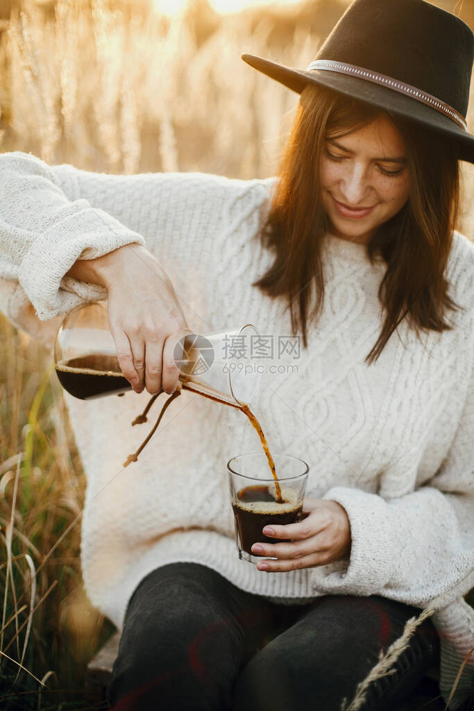 时髦的女人把热咖啡倒在玻璃杯里图片