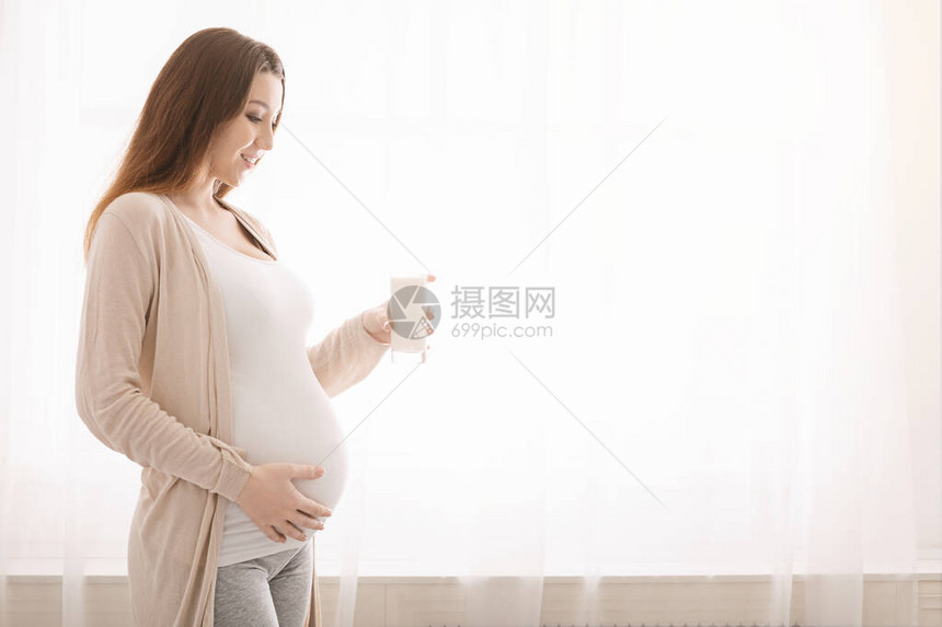 健康营养和怀孕年轻孕妇喝着一杯新鲜牛奶图片