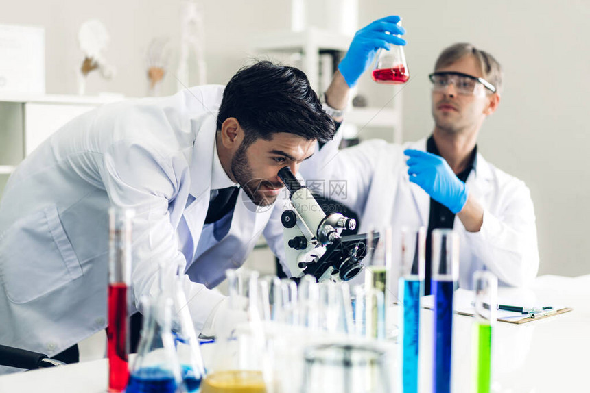 专业的两名科学家在现代实验室进行化学实验的同时进行研究并使用显微镜在试管中图片