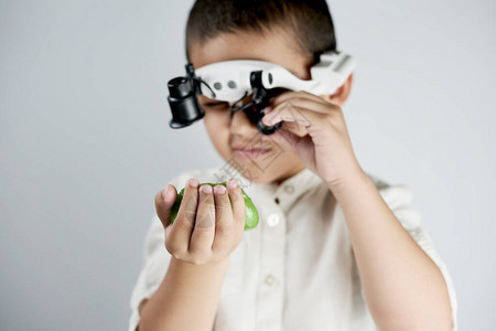 小男孩拿着黏液透过特别放大镜戴耳机看望图片