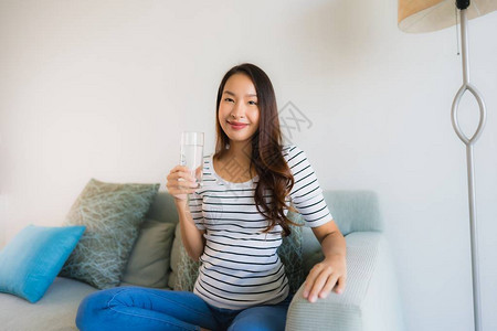 内地客厅沙发上用水杯装着饮用水杯的美丽的年轻图片