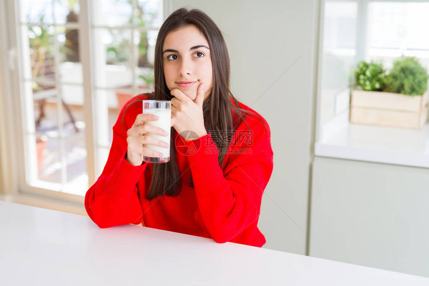 美丽的年轻女士喝着一杯新鲜奶水面露一脸严肃的表情思考问题非图片