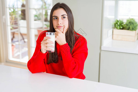 美丽的年轻女士喝着一杯新鲜奶水面露一脸严肃的表情思考问题非图片