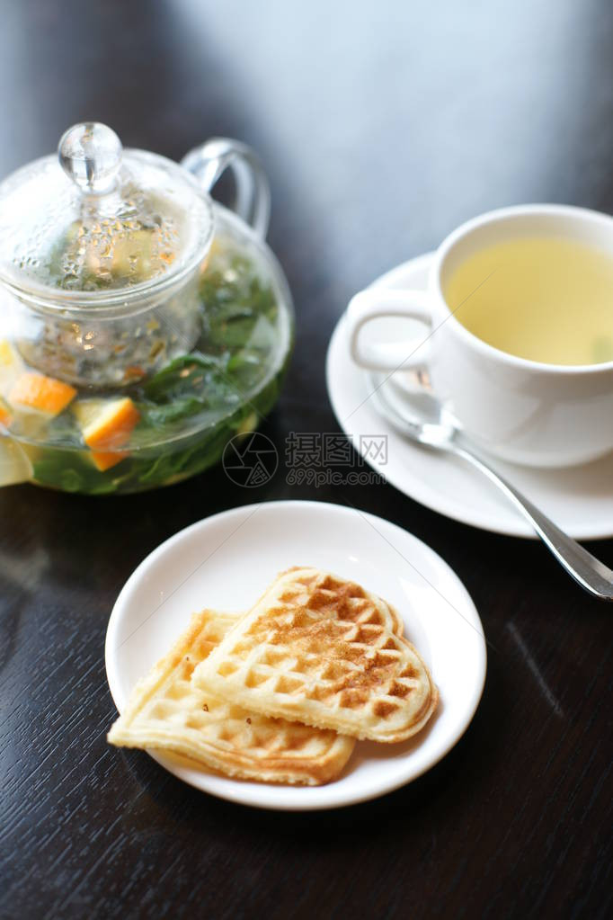 黑桌背景的烤华夫饼加玻璃茶图片