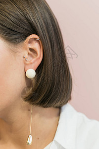 戴金口音的珍珠耳环在粉色糊面背景棕头发在四角图片