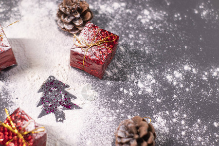 雪中的圣诞装饰品礼物和松果以及圣诞树的轮廓圣诞气氛背景图片