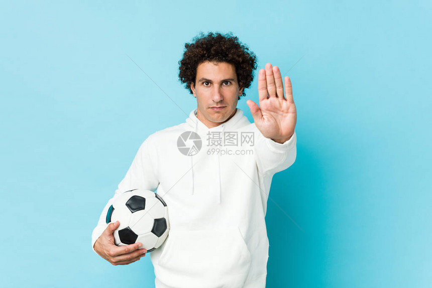 运动男子拿着足球站着伸展的手举着图片