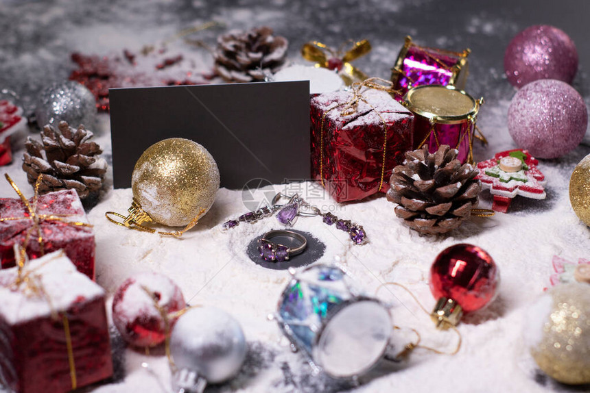 紫色首饰戒指和耳环旁边是雪中的新年装饰品圣诞树球雪花礼物球果圣诞气氛图片