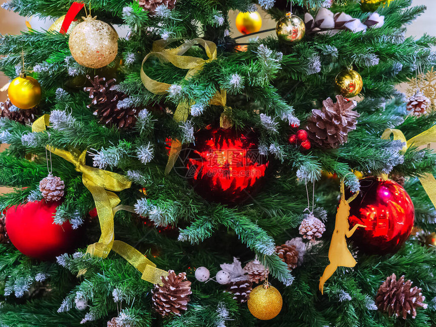 圣诞树上装饰着红色和金色的球丝带和松果图片
