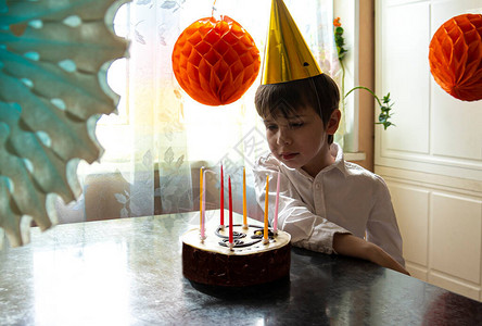 心烦意乱的男孩正在看生日蛋糕他一个人过生日在大流行和自我隔离期间没有朋图片