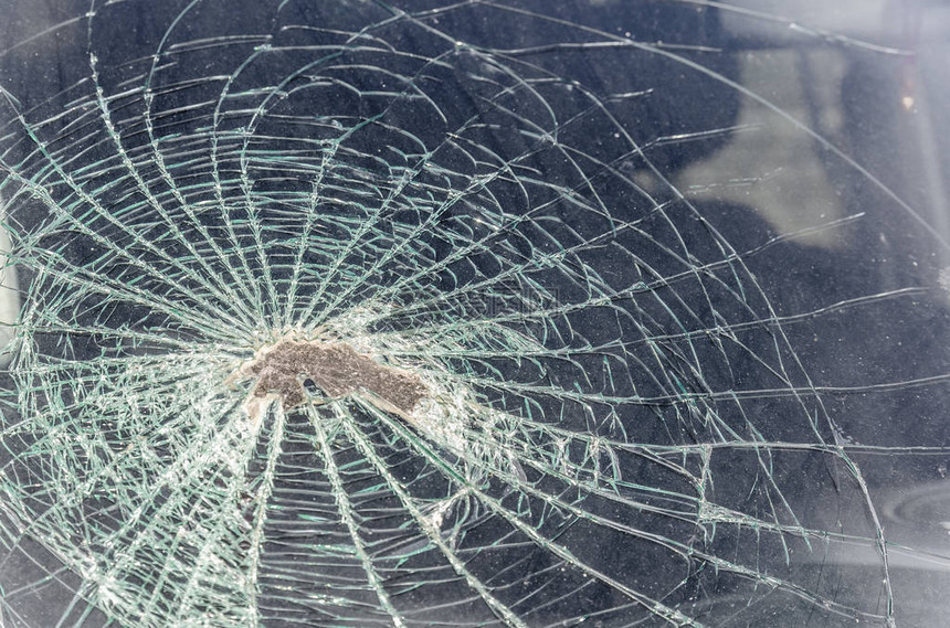 一块石头或一块鹅卵石在挡风玻璃高速飞入汽车时砸碎了它挡风玻璃破损的碎片和痕迹纹理裂缝图片