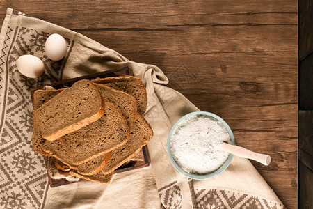 鸡蛋与面包片和桌布上的面粉碗图片