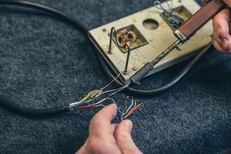 人手和烙铁工具和电线的特写在家焊接过程图片