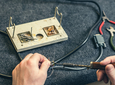 人手和烙铁工具和电线的特写在家焊接过程图片