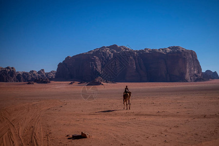 骑骆驼穿越沙漠景观的人背景图片