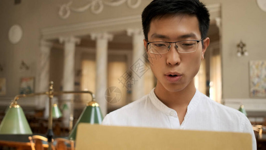 亚洲学生在大学图书馆以考试成绩打开信封图片