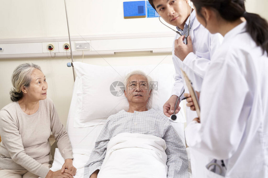 检查在医院病房中讨论其病情的老年病人的年轻青医图片