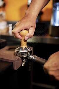 在餐馆将咖啡粉碎成粉末时使用研磨机逼近男图片