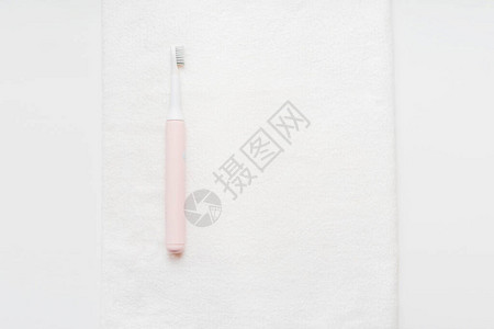 粉色电动振牙刷用于在白毛巾上刷除图片