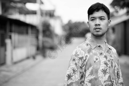 身着夏威夷衬衫的亚洲青年旅游男子在街上黑白露天图片