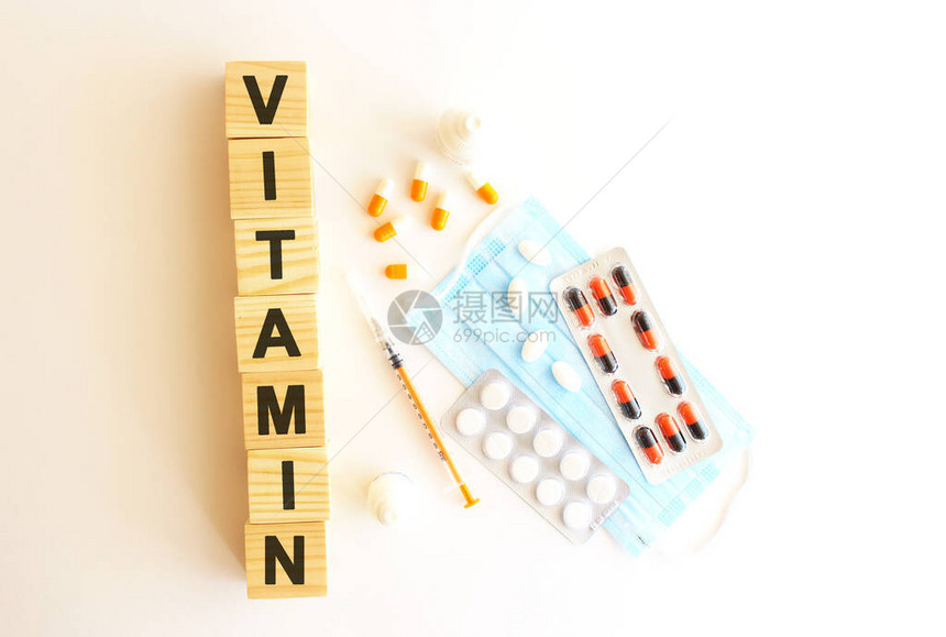 VITAMIN这个词是用白色背景的木制立方体配有药品和医疗面图片