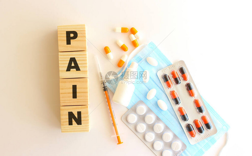 PAIN是用白色背景的木制立方体配有药品和医疗面图片