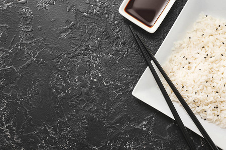 深色背景中煮米饭和酱油的盘子图片