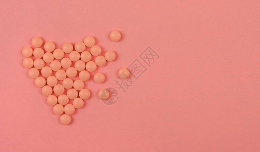 世界心脏日的概念医学背景粉红色药丸以粉红色背景上的心形平躺心脏健康概图片