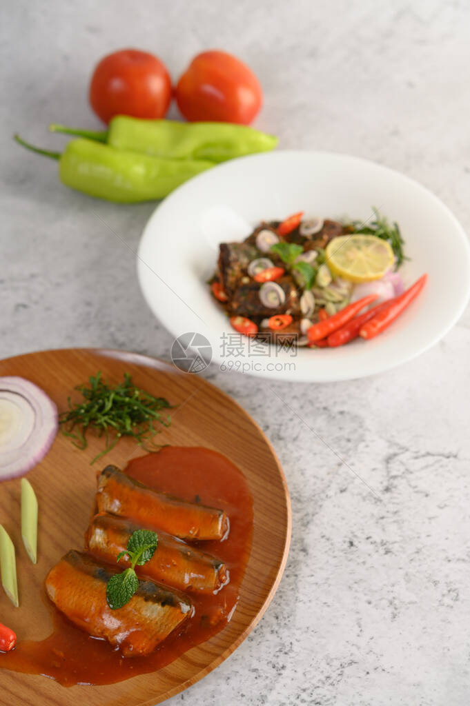 模糊的辛辣沙丁鱼罐头沙拉配香草成分在白盘图片